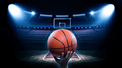 spotlights pointed at a basketball with an empty court and stadium in background - March Madness trademarks concept